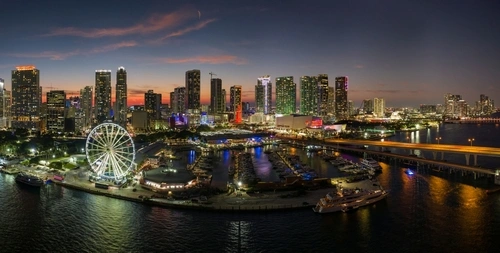 Miami marina harbor and skyscrapers of Brickell, city financial center. Skyviews Miami Observation Wheel at Bayside Marketplace in Biscayne Bay water at night.